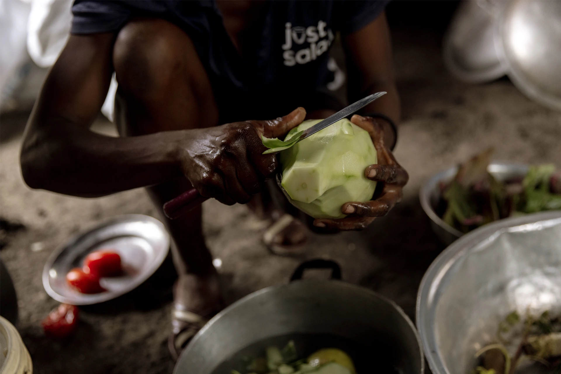 A Haitian woman peels vegetables as she prepares food for the students at school.