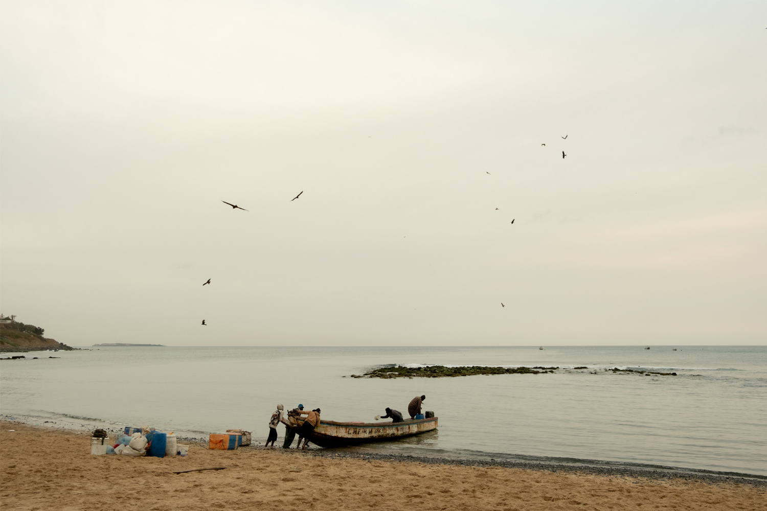 A group of fisherman pull their boat onto shore to unload the day's catch in Oakam, Senegal. 